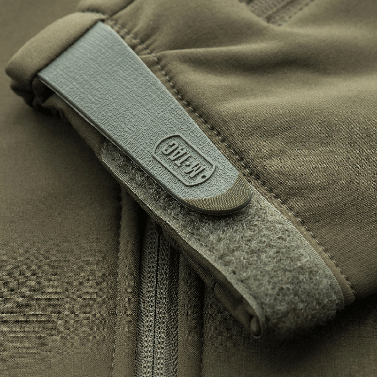 Lähikuva M-Tac Soft Shell Police Jakkeesta beigeenä, näyttää vetoketjun ja hihan tarrakiinnityksen.