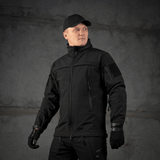 Mies pukeutuneena M-Tac Soft Shell Police Jakkeen valmis toimintaan, suojattuna tuulelta ja siltä säältä säädettävän hupun kanssa.