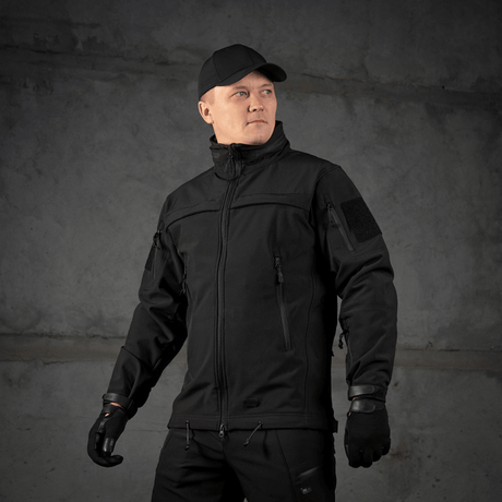 Mies pukeutuneena M-Tac Soft Shell Police Jakkeen valmis toimintaan, suojattuna tuulelta ja siltä säältä säädettävän hupun kanssa.