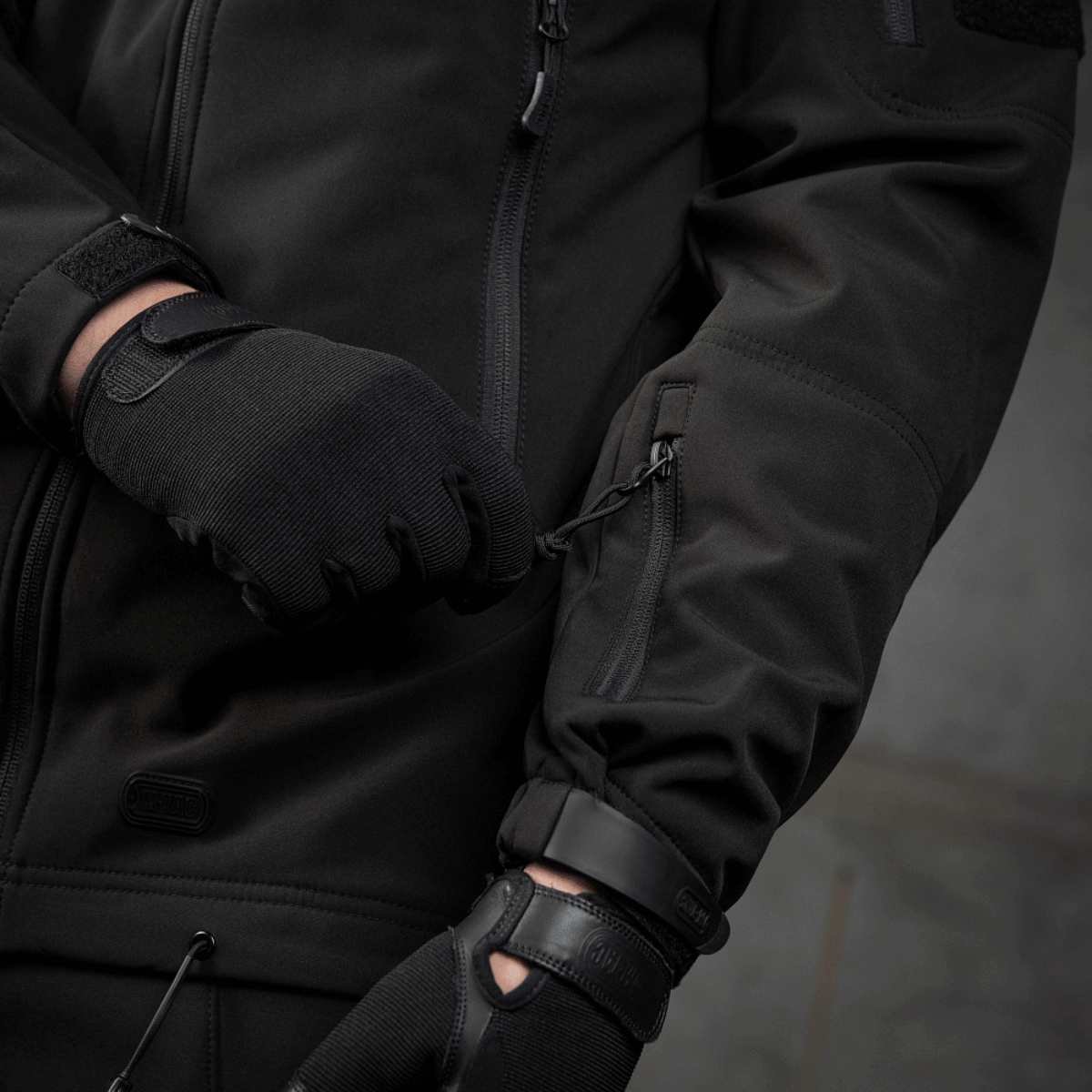 Yksityiskohtia M-Tac Soft Shell Police Jakkeesta taskun vetoketjulla, sisäisellä polyuretaanikalvolla ja säädettävillä ominaisuuksilla.