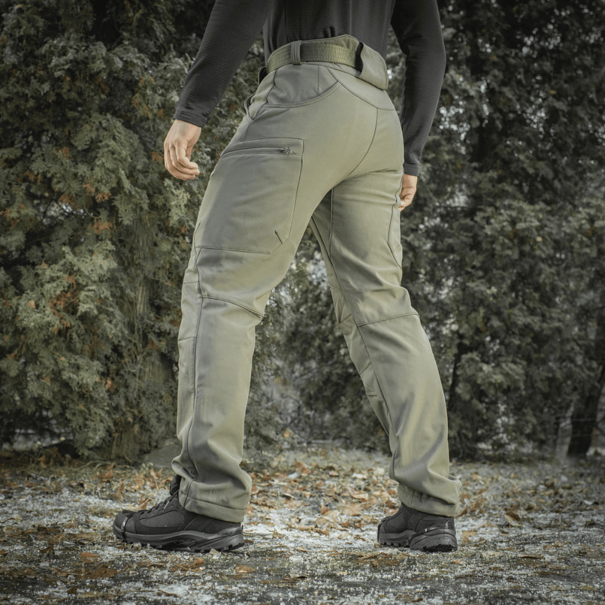 M-Tac Soft Shell Vinter -housut metsäympäristössä, korostaa housujen lämpöä ja mukavuutta kylmissä, tuulisissa olosuhteissa.