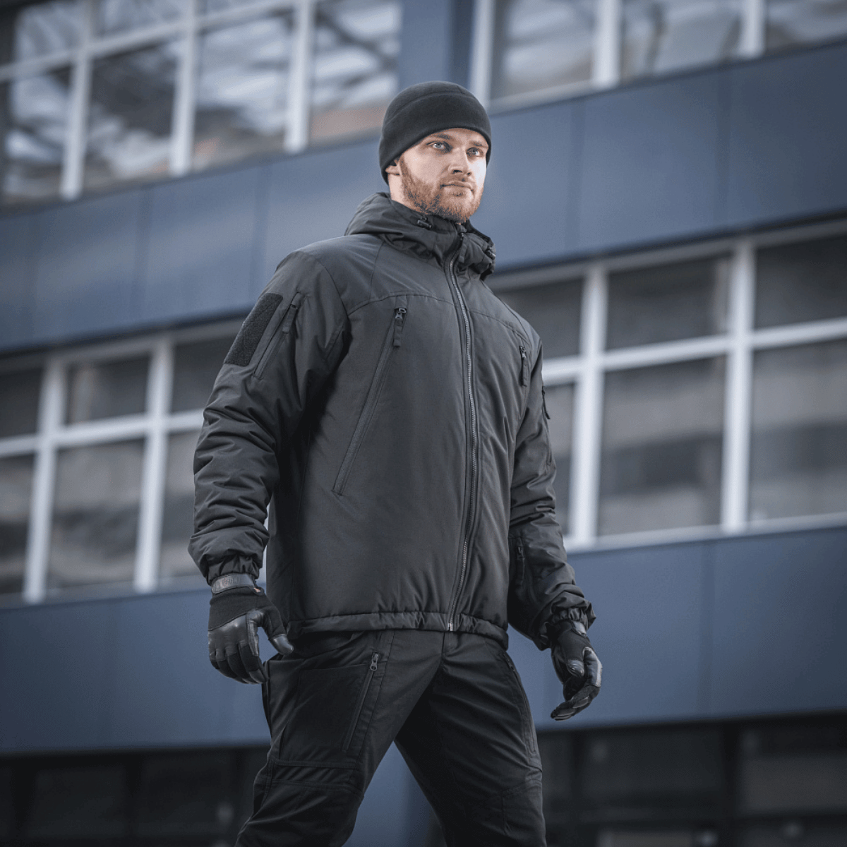 Mies pukeutuneena M-Tac Alpha Gen.III Pro -talvitakkiin kaupunkiympäristössä, sopii äärimmäisiin olosuhteisiin mukavuudella ja vettä hylkivällä materiaalilla.