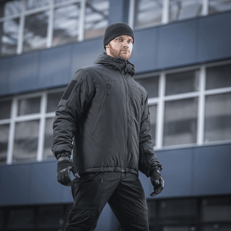 Mies pukeutuneena M-Tac Alpha Gen.III Pro -talvitakkiin kaupunkiympäristössä, sopii äärimmäisiin olosuhteisiin mukavuudella ja vettä hylkivällä materiaalilla.