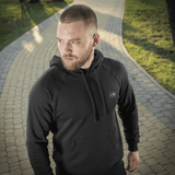 Mies M-Tac Cotton Raglan -hupparissa polulla vihreässä puistossa, mukava arki- ja urheiluvaate, 100 % puuvillaa.