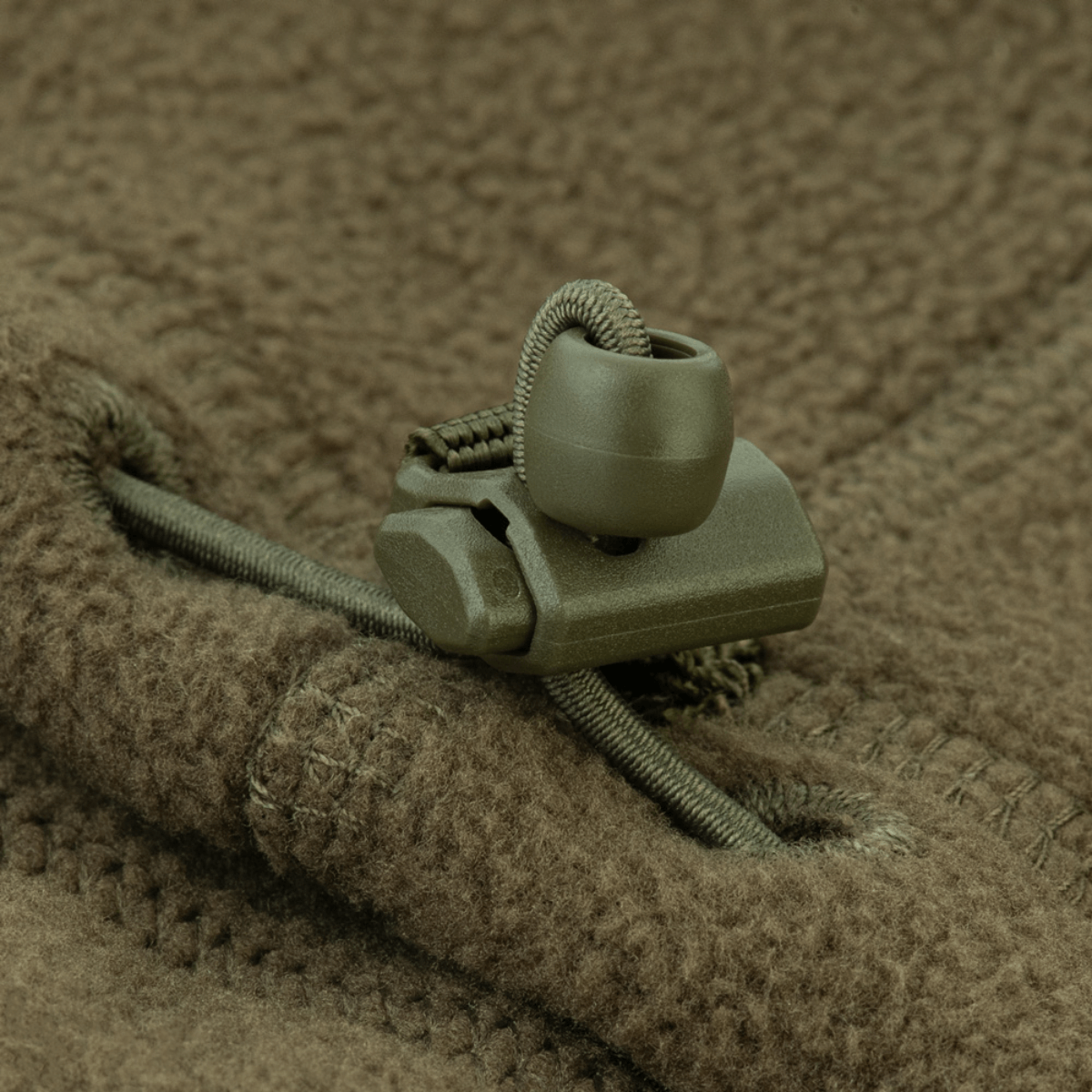 Yksityiskohta säädettävästä nyöristä M-Tac Anatomisk Snood Justerbar Elite Fleece (320 g/m²), näyttää robustin vihreän muotoilun.