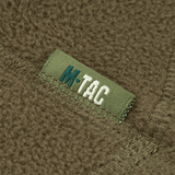 Lähikuva M-Tac Anatomisk Snood Justerbar Elite Fleece (320 g/m²) näkyvillä kangas-yksityiskohdilla ja logolla vihreällä taustalla.