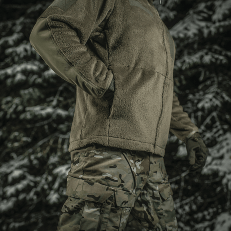 M-Tac Battle Fleece Polartec -takki käytössä armeijassa metsäympäristössä, korostaa kestävyyttä ja mukavuutta.