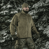 Mies metsässä kantaa M-Tac Battle Fleece Polartec -takkia, sopii sotilas- ja poliisikäyttöön, korostaa mukavuutta ja kestävyyttä talvisessa maisemassa.