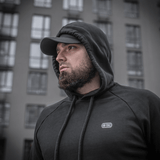 Mies pukeutuneena M-Tac Cotton Raglan Hard Hoodieen, 100% puuvillaa fleece-vuorella, tyylikäs arkipaita, nähty rakennuksen edessä.