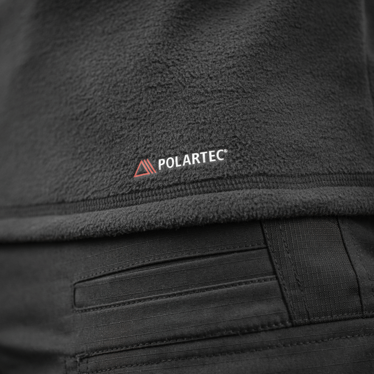 Yksityiskohta M-Tac Delta Polartec Raglan -takista, tehty Polartec-fleecestä Polartec-logolla.