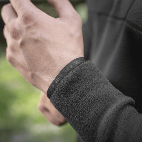 Mies pukeutuneena M-Tac Delta Polartec Raglan -takkiin, näyttää fleece-yksityiskohdan ja joustavan nauhan, soveltuu ulkoiluun.