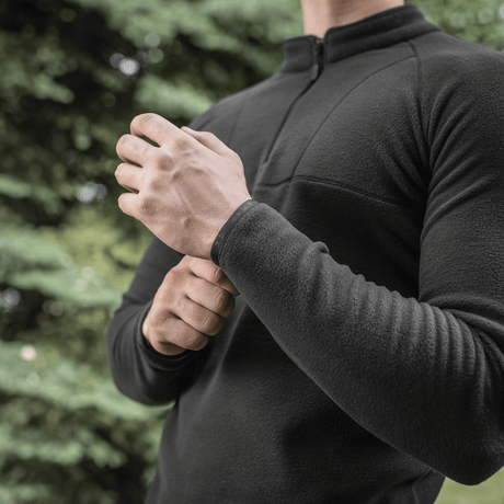 Mies pukeutuneena mustaan M-Tac Delta Polartec Raglan -takkiin Micro Series -fleecessä, täydellinen arkeen ja ulkoiluun, vetoketju ja korkea kaulus.