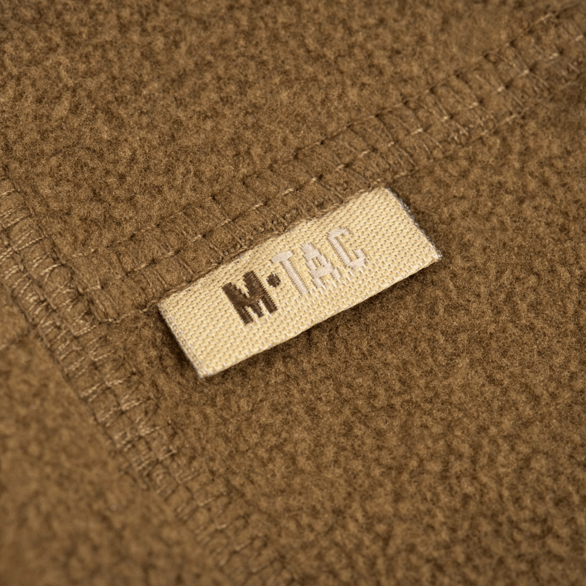 Lähikuva M-Tac Fleece Neck Gaiter med Snor, näyttää pehmeän fleecemateriaalin ja merkkietiketin.