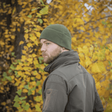 Mies pukeutuneena M-Tac Fleece Polartec Watch Cap -pipoon metsässä syksyn lehtien keskellä.