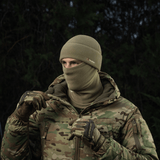 Henkilö pukeutuneena M-Tac Fleece Polartec Watch Cap -pipoon kylmässä ulkoilmassa, sopii talviaktiviteetteihin, maastokuvioinen takki.