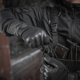 Henkilö pukeutuneena M-Tac Handsker Police Gen.2 en taktiseen tilanteeseen; liukumaton ote ja säädettävä Velcro, suunniteltu poliisille ja turvallisuustyöhön.