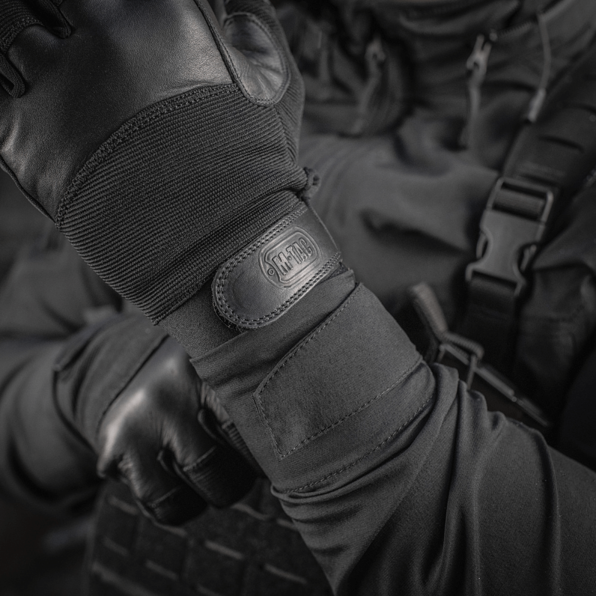 M-Tac Handsker Police Gen.2 taktiset käsineet, suunniteltu nahalla ja joustavilla paneeleilla, lähikuva kädestä Velcrolla ja logolla.