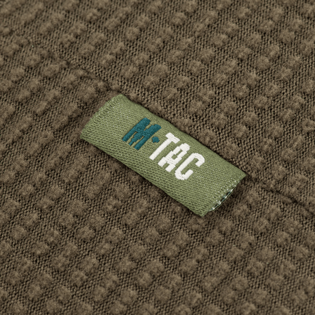 Lähikuva M-Tac Hjelm Watch Cap Polartec -tekstiilirakenteesta M-Tac-logolla, ihanteellinen kylmään säähän ja mukavuutta kypärän alla.