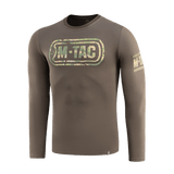 M-Tac T-Shirt Logo Long Sleeve maastokuvioituna, ikoninen M-Tac-logo ja slogan 'Born by Revolution – Hardened by War' hihassa.
