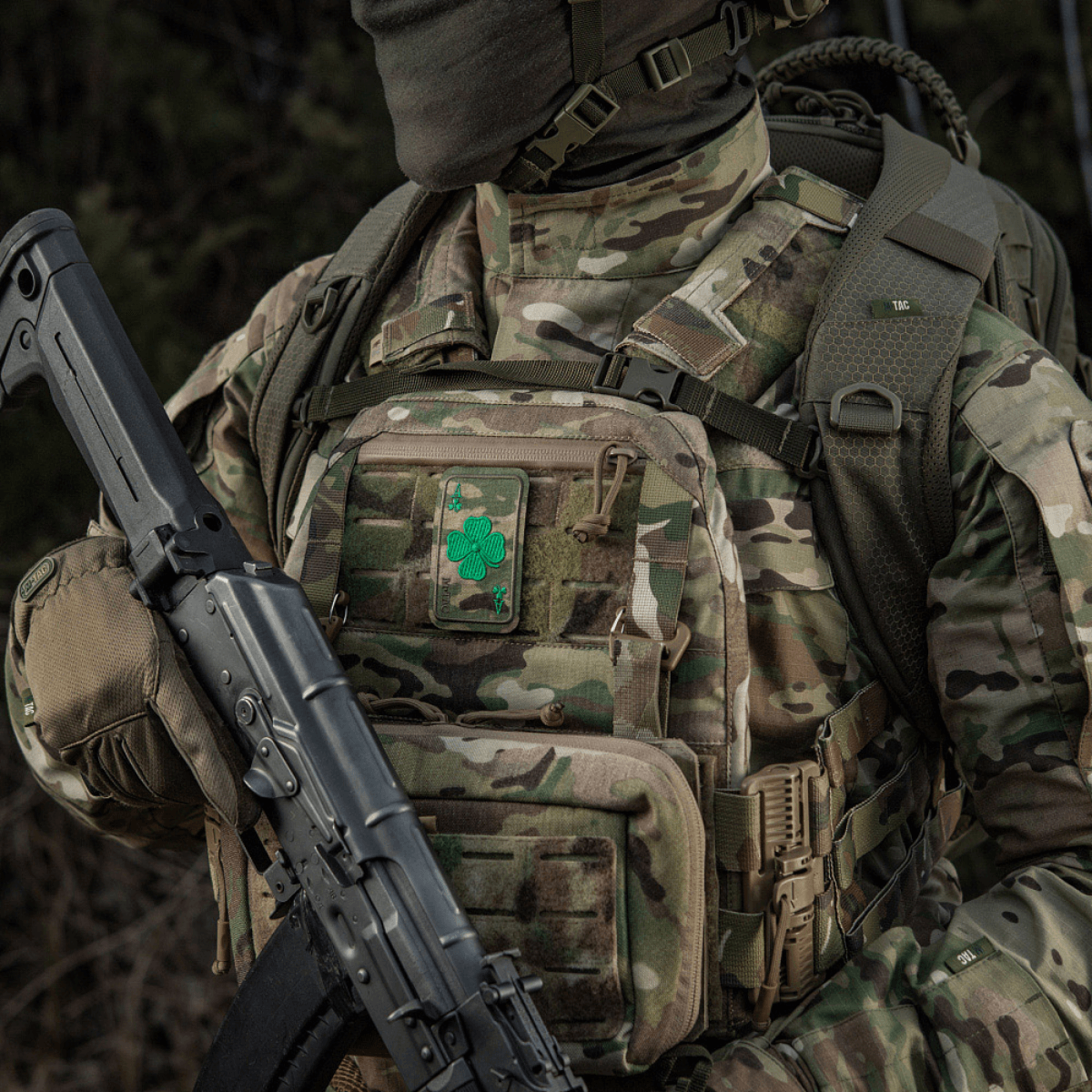 Militaarivarusteet M-Tac Patch Lucky Card (brodeerattu) apilanlehdellä, kiinnitetty Velcrolla maastokuvioituun reppuun.