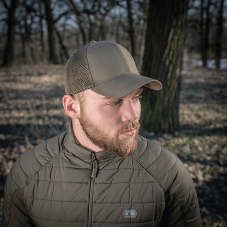 M-Tac Mesh Flex Ripstop Baseball Cap en käytössä metsässä, osoittaa kestävyyden ja hyvän ilmankierron ripstop- ja mesh-suunnittelulla.