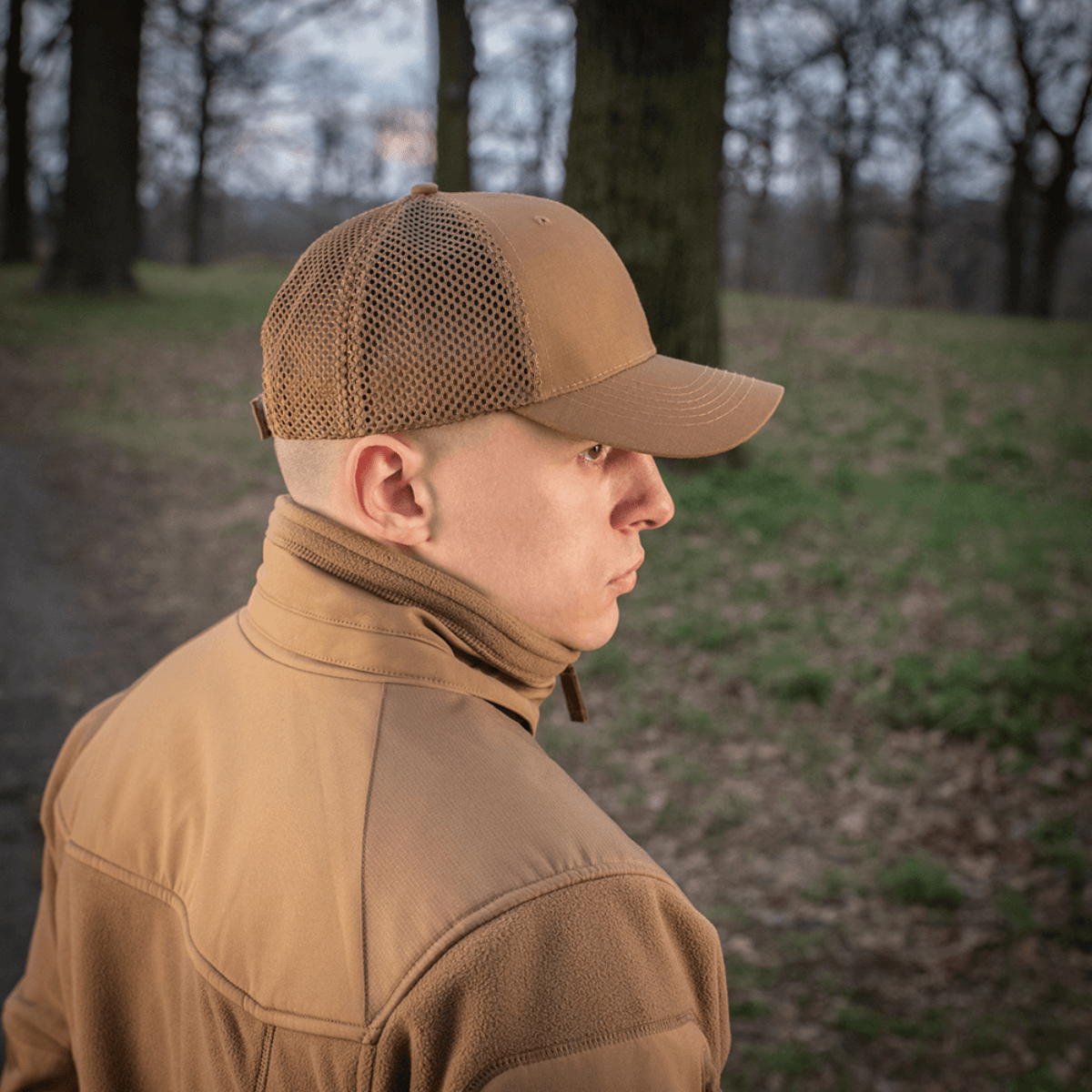 Mies käyttää M-Tac Mesh Flex Ripstop Baseball Capia metsässä; näkyvillä kypärän mesh-paneelit ja kestävä lippa.
