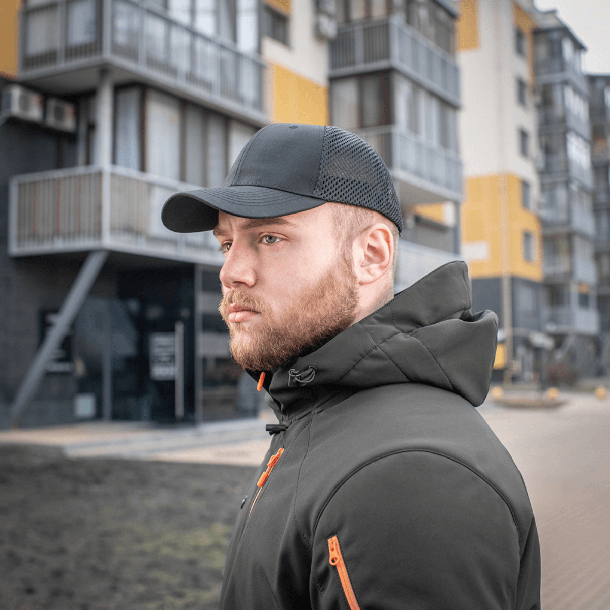 Mies mustassa M-Tac Mesh Flex Ripstop Baseball Cap en kaupungin edessä, kuva näyttää ulkoiluun liittyvää kestävyyttä ja tyyliä.