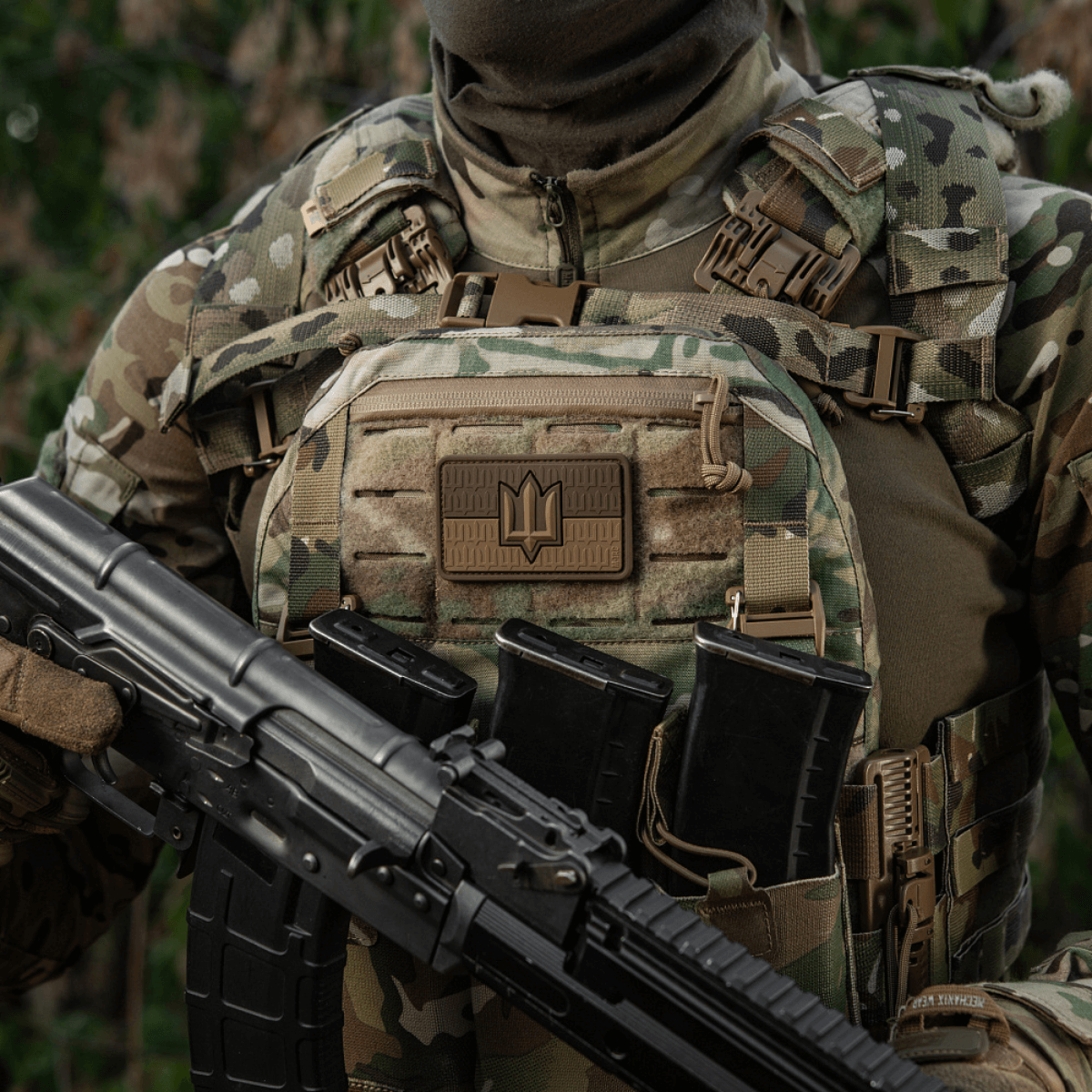 Sotilas maastoliivissä, jossa M-Tac-tarra Ukraine Flag ZSU Trident PVC, pitää asetta, symboloi Ukrainan ylpeyttä ja perintöä