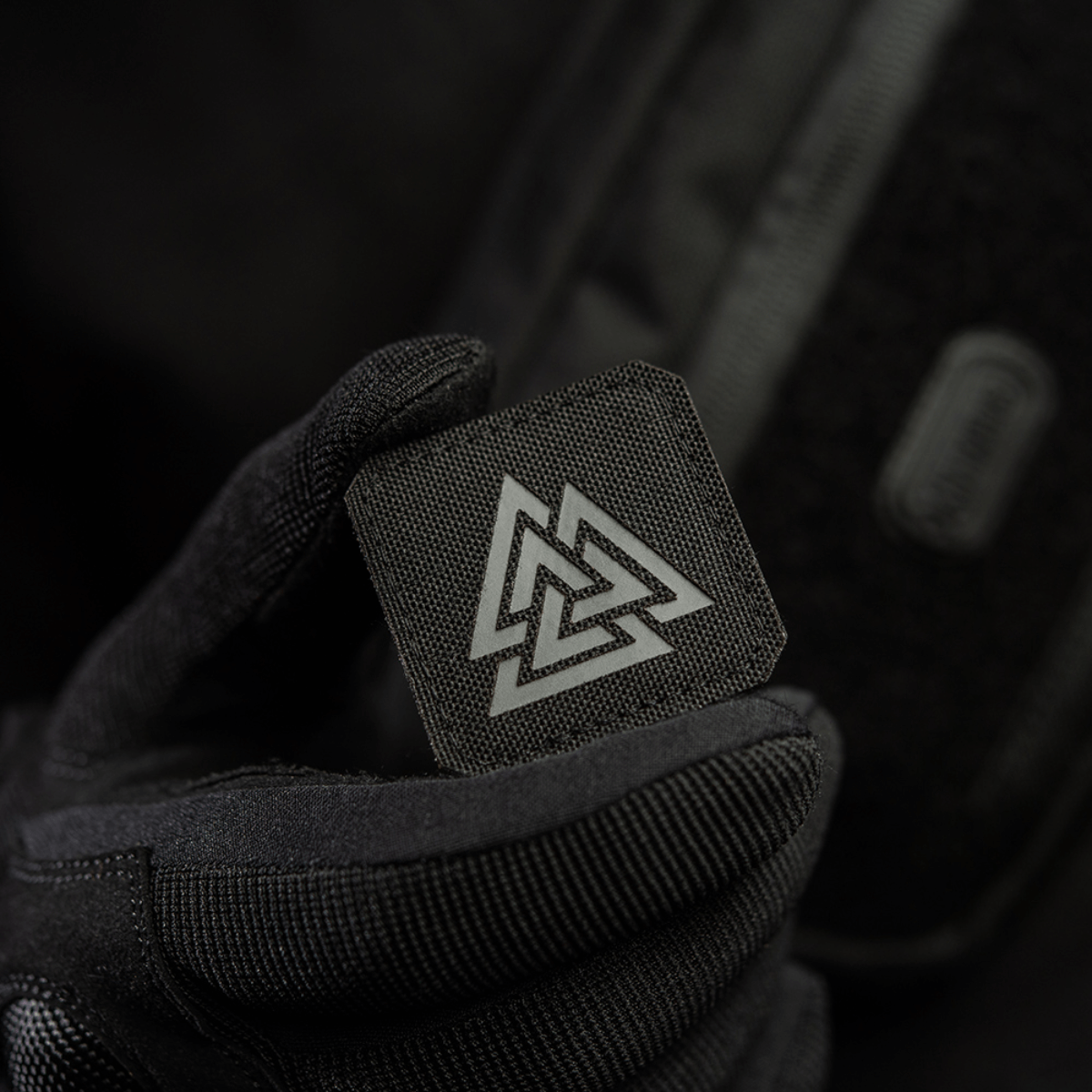 M-Tac Patch Valknut Laser Cut Odin -symboli Völknot-kuviolla mustalla taustalla, pidetty en kädellä, jossa musta hansikas