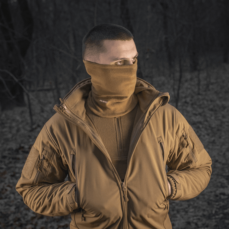Mies käyttää M-Tac Tube Scarf Polartec -tuubia kasvomaskina ulkona metsässä, sopii kylmiin vuodenaikoihin, Polartec-fleece.