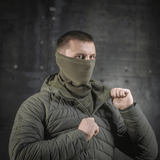 Miehellä on M-Tac Polartec Anatomic Tube Scarf kasvomaskina vihreässä ympäristössä.
