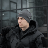 Mies lämpimässä takissa ja pipossa harmaassa säässä. M-Tac Polartec Lang Tubehalstørklæde.