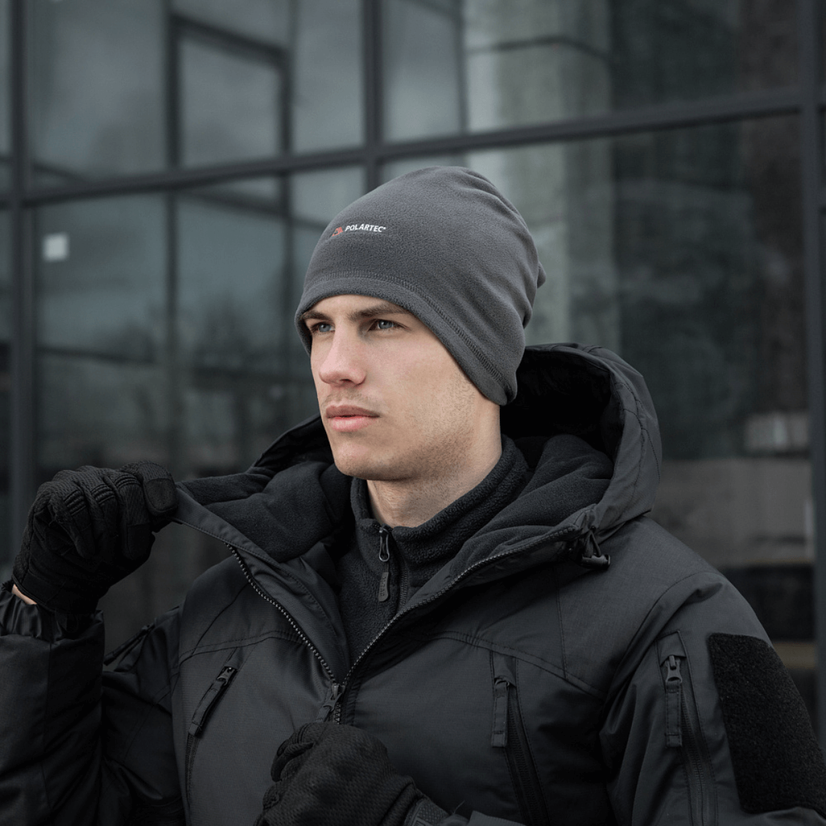 Mies lämpimässä takissa ja pipossa harmaassa säässä. M-Tac Polartec Lang Tubehalstørklæde.