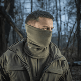 Mies käyttää M-Tac Tube Scarf Polartec -tuubia kasvomaskina metsässä, suojaa kylmältä ja tuulelta ulkoillessa.