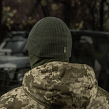 Henkilö käyttää M-Tac Rip-Stop Fleece Hjelmlineriä, maastokuviollinen takki ulkoilmassa