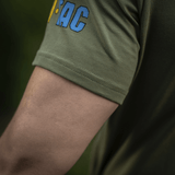 Lähikuva hihasta M-Tac T-Shirt Quadcopter, logo sinikeltaisena oliivinvihreällä taustalla, näyttää puuvilla-elastaani-seoksen.