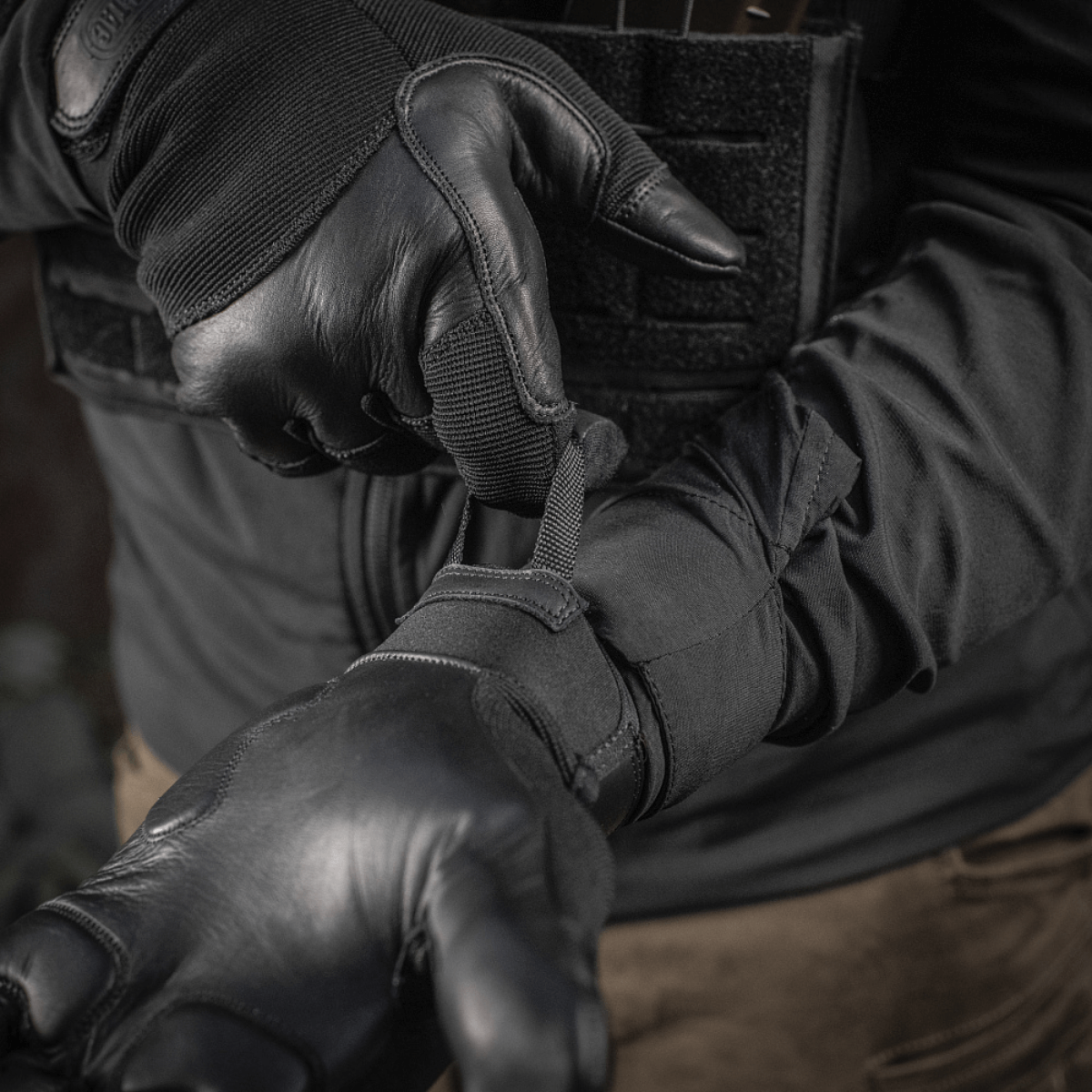 Henkilö pukeutuneena M-Tac Handsker Police Gen.2 Velcro-säädöllä täydellistä istuvuutta ja liukumaton ote turvallisuutta ja aseenkäsittelyä varten.