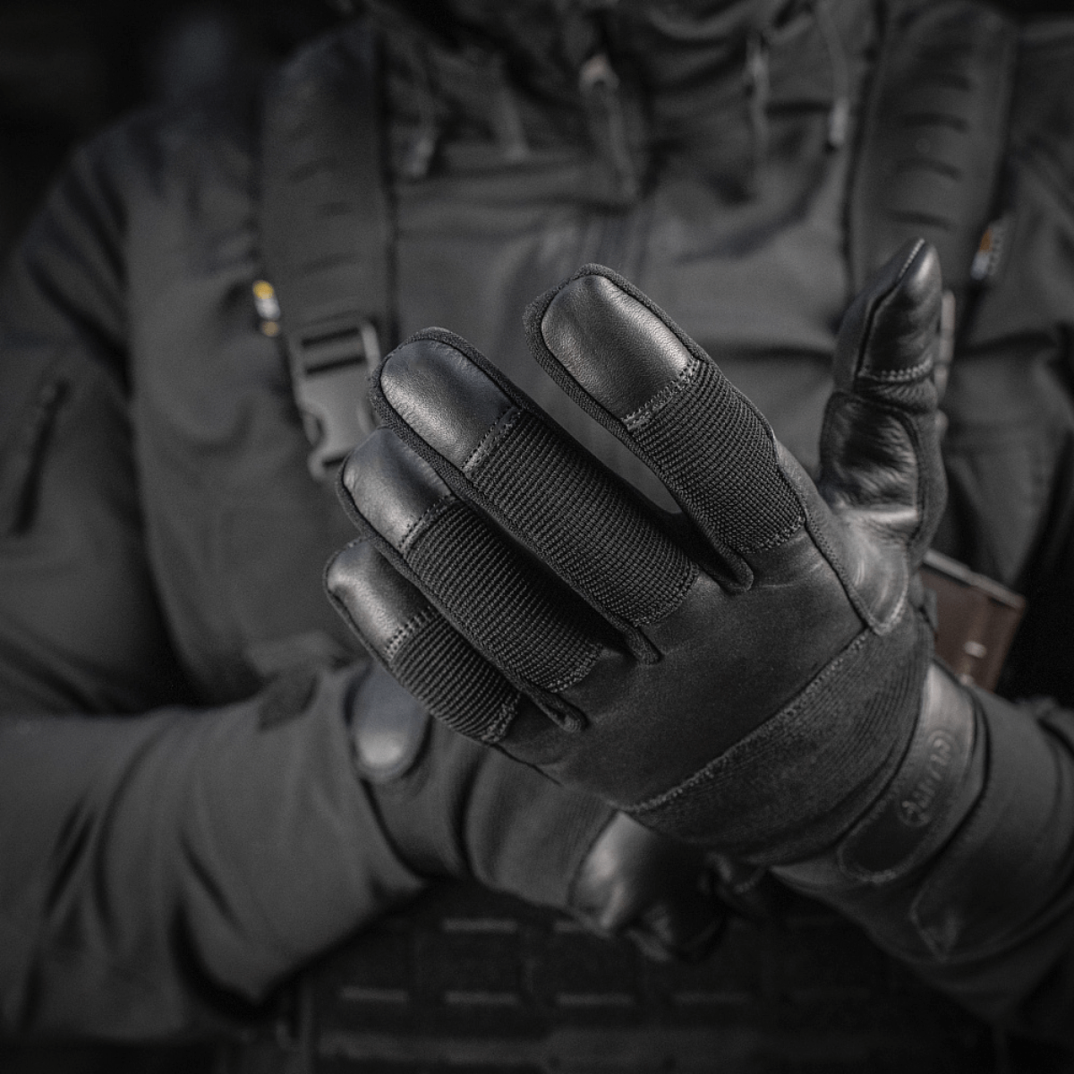 Henkilö pukeutuneena M-Tac Handsker Police Gen.2 en, suunniteltu turvallisuuteen ja mukavuuteen taktisiin tilanteisiin.