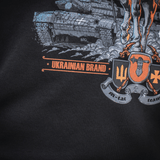 Yksityiskohta M-Tac T-Shirt Steel Knightistä, esittää Ukrainan teräsratsastaja-designin: ritari, tankki ja tridentti-embleemi kunnianosoituksena Ukrainan joukoille.