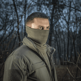 Mies metsässä käyttäen M-Tac Tube Scarf Polartec -tuubihuivia, tyylikäs ja lämmin kauluri ulkoiluun kylminä vuodenaikoina.