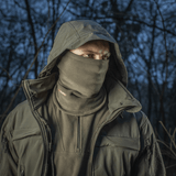 Mies metsässä käyttäen M-Tac Tube Scarf Polartec -kauluria, suoja säätä vastaan Polartec Micro Series fleece -materiaalista, ulkoilutyyli.