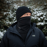 Mies käyttää M-Tac Tube Scarf Polartec -kauluria lumisessa maisemassa, suojaten kylmältä yhdessä takin kanssa.