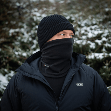 Mies käyttää M-Tac Tube Scarf Polartec -kauluria lumisessa maisemassa, suojaten kylmältä yhdessä takin kanssa.