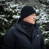 Mies pukeutuneena M-Tac Tube Scarf Polartec -kauluriin lumipeitteisten kuusten edessä; lämmin monitoiminen kauluri talvikäyttöön.