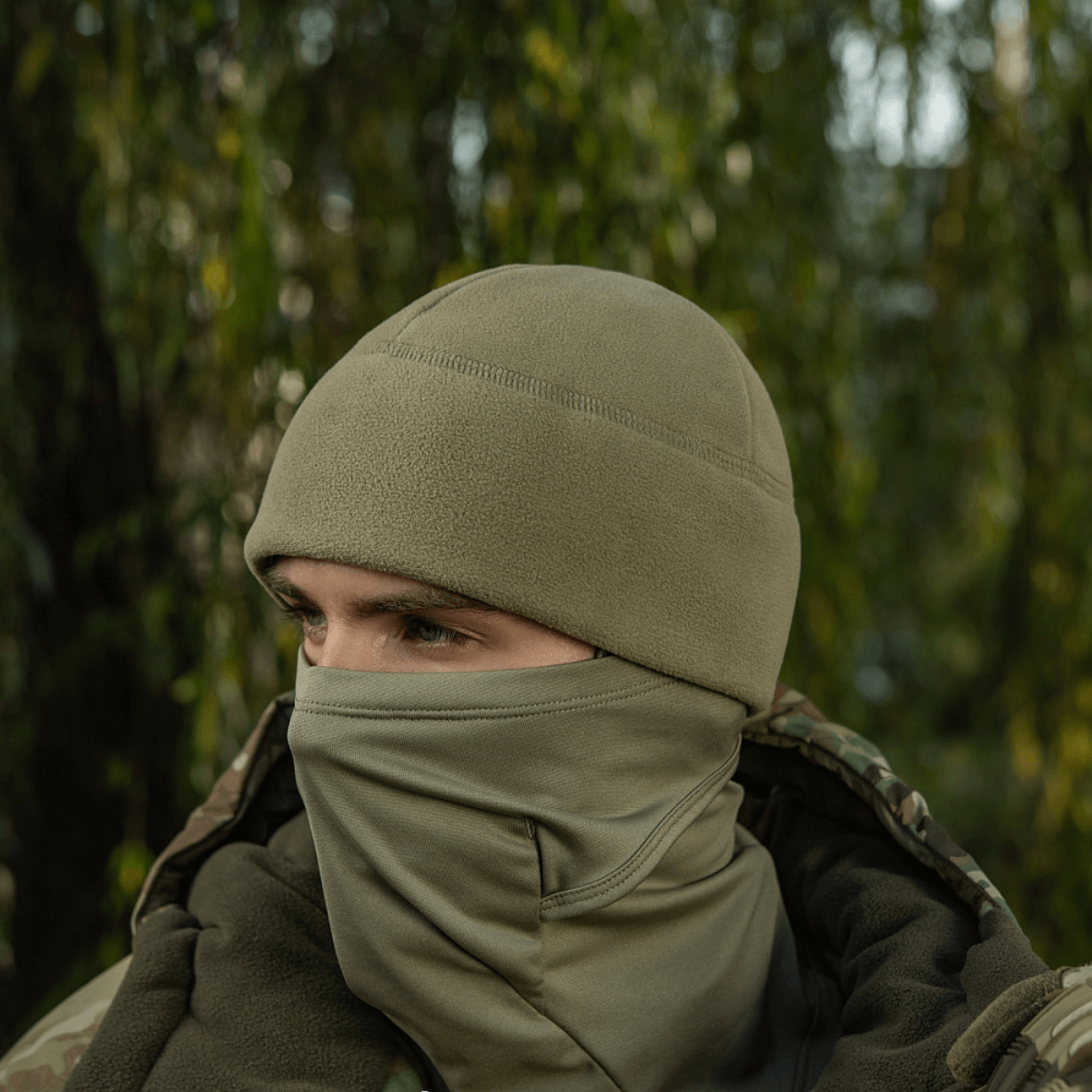 Henkilö käyttää M-Tac Watch Cap Elite Fleece Beanie Hat Slimtexiä luonnossa, sopii kylmään ja taktiseen käyttöön, maastokuvioidun takin kanssa