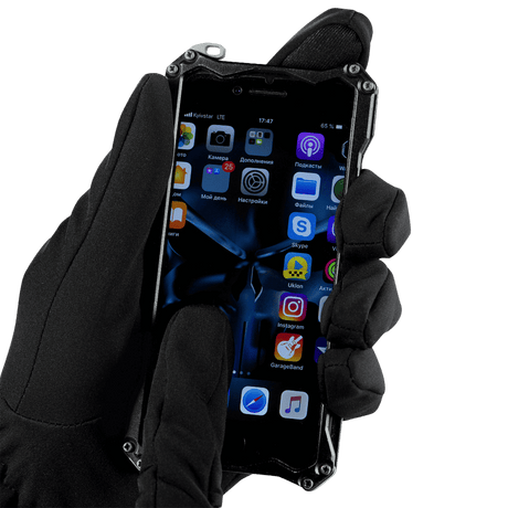 Henkilö käyttää M-Tac Vinterhandsker Soft Shell -hanskoja älypuhelimen kanssa kylmässä säässä.