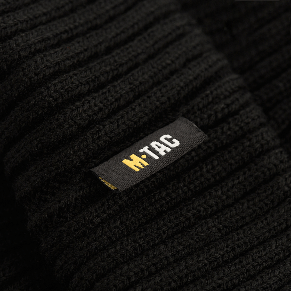 Lähikuva M-Tac Watch Cap 100% Akryl mustasta kankaasta ja M-Tac-logosta, ihanteellinen kylmään säähän. Matala malli ja teollinen kaksinkertainen neulos.