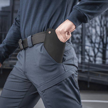 Henkilö pukeutuneena M-Tac housuihin Sahara Flex Light käsi taskussa ulkona.