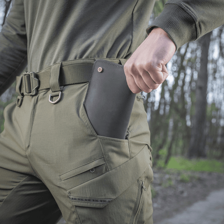 Henkilö pukeutuneena M-Tac Aggressor Summer Flex -housuihin, puhelin taskussa ulkoilupolulla.