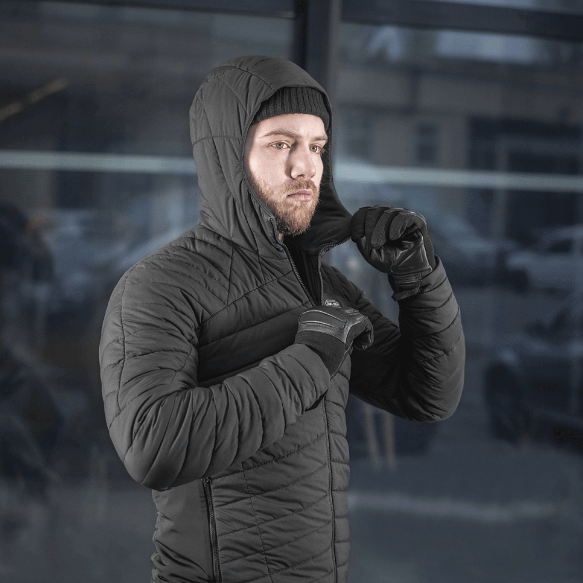 Mies pukeutuneena mustaan M-Tac Jarl -takkiin, sopii suojaksi kylmää ja tuulta vastaan, valmistettu Toray mechanical stretch -nylonista ja G-Loft-täytteellä.